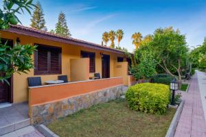 a yellow house with a stone wall at Ozlem Garden Hotel in Side
