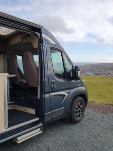 a blue van parked on the side of a hill at Adventure Campervan to Explore the Faroes in Hoyvík