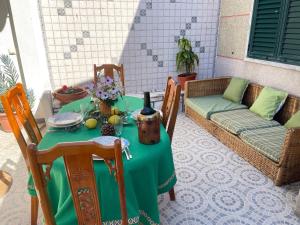 a table with a green table cloth and a couch at Vino Domus in Cabeção