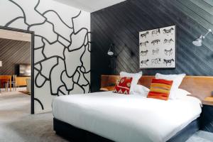 a bedroom with a large white bed and a wall at Totem, Friendly Hotel & Spa in Flaine