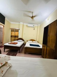 a bedroom with two beds and a ceiling fan at Green View Resthouse in Sreemangal