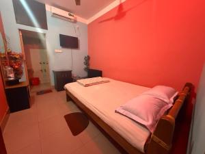 a bedroom with red walls and a bed with two pillows at Green View Resthouse in Sreemangal