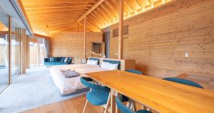 a room with a bed and a table and chairs at ヴィラブラマーレ in Kitahiroshima