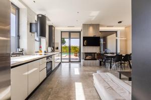 a kitchen with white cabinets and a dining room at Villa AMMA Pool & Jacuzzi by PikHost in Draç