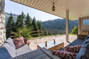 a patio with couches and a table and a view at Ferienhaus am Waldrand in Damuls
