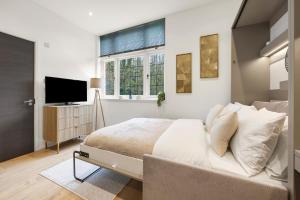 a white bedroom with a bed and a television at Modern 2 Bed Apartment by MCF in Merstham