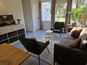 a living room with a couch and chairs and a tv at Puur 38 in Simpelveld