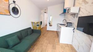 a living room with a green couch and a kitchen at Cascais Garden House 105 in Cascais