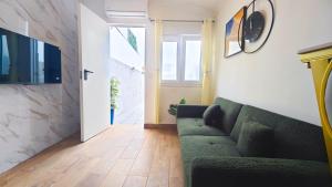 a living room with a green couch and a hallway at Cascais Garden House 105 in Cascais