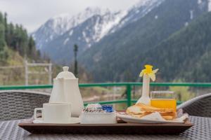 a tray with breakfast food and a glass of orange juice at Fimi hotel aru valley pahalgam in Ārau