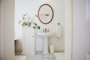 a white bathroom with a sink and a mirror at Charming Historical Cottage in Graaff-Reinet +27 photos