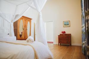 a bedroom with a white bed and a dresser at Charming Historical Cottage in Graaff-Reinet