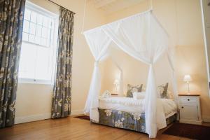 a bedroom with a canopy bed and a window at Charming Historical Cottage in Graaff-Reinet