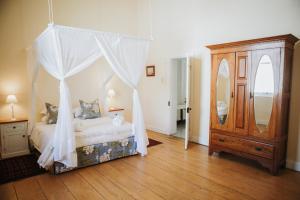 a bedroom with a canopy bed and a wooden floor at Charming Historical Cottage in Graaff-Reinet