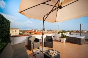 a patio with an umbrella and chairs on a roof at Terrazza vista Vesuvio e Capri con Jacuzzi privata in Naples +23 photos