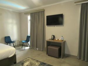 a hotel room with a bed and a television on the wall at Eden Hotel on Florida in Durban