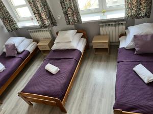 two beds in a room with two windows at Jasna Hotelik self check-in in Warsaw