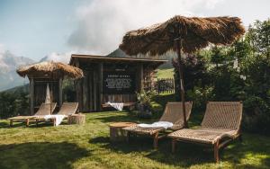 a group of chairs and an umbrella in the grass at Jufenalm BOHO & Wellnesshotel in Maria Alm am Steinernen Meer +261 photos