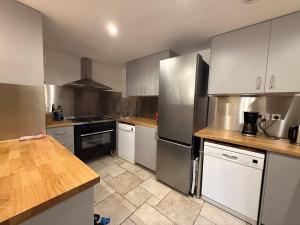 a kitchen with white cabinets and stainless steel appliances at Maison Caramel Chalet in Landry