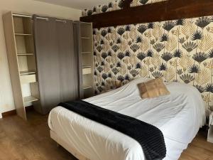 a bedroom with a white bed with a patterned wall at Chez PRESSOIRS in Mesnac +2 photos
