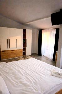 a bedroom with a large white bed and a window at Nesto Rooms in Sighetu Marmaţiei