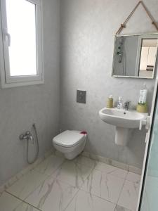 a white bathroom with a toilet and a sink at Villa Sassi in Nabeul