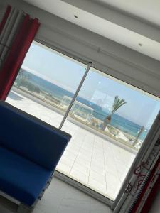 a window with a view of the ocean and a palm tree at Villa Sassi in Nabeul
