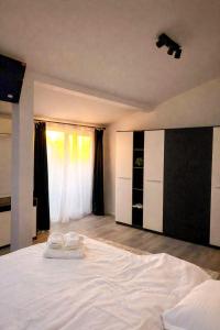 a bedroom with a large white bed with two towels on it at Nesto Rooms in Sighetu Marmaţiei