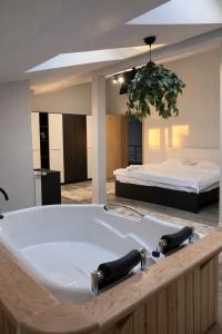 a bathroom with a bath tub with a bed in the background at Nesto Rooms in Sighetu Marmaţiei +23 photos