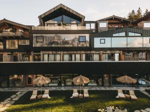 a building with chairs and umbrellas in front of it at Jufenalm BOHO & Wellnesshotel in Maria Alm am Steinernen Meer