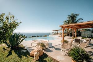 a pool with chairs and a pavilion and the ocean at Villa Michaela con piscina privata e vista mare in Capo Vaticano