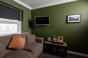 a living room with green walls and a couch and a table at Old Ship Inn Hackney in London