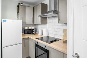a kitchen with white cabinets and a stove top oven at Family-Friendly Chorlton Apartment with Free Street Parking in Sale