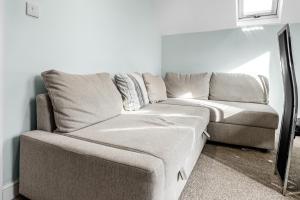 a grey couch in a living room with a window at Family-Friendly Chorlton Apartment with Free Street Parking in Sale