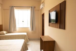 a bedroom with two beds and a tv on the wall at Hotel Primavera Palace in Salinas