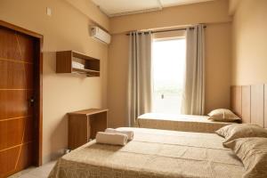 two beds in a room with a window at Hotel Primavera Palace in Salinas