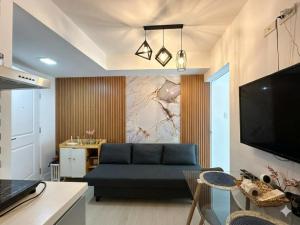 a living room with a blue couch and a tv at Metro Manila Cityscape Charm at Azure Urban Resort Paranaque near NAIA Airport in Manila