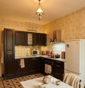 a kitchen with black cabinets and a white refrigerator at La Miséricorde-Deluxe room with kids room in Coutances