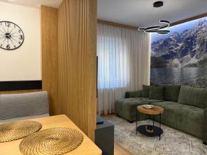 a living room with a couch and a clock on the wall at City Garden II in Kolašin