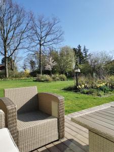 a wicker chair sitting on a deck next to a park at TheGilgahouse Gardenroom nr 2 in Nakskov