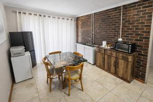 a kitchen with a table and chairs and a brick wall at Work, Rest, Repeat, Comfortable 2BR Flat in Kathu in Kathu
