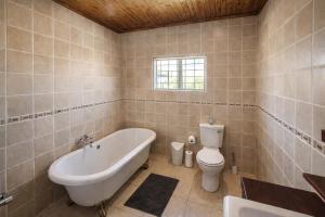 a bathroom with a tub and a toilet and a sink at Work, Rest, Repeat, Comfortable 2BR Flat in Kathu in Kathu