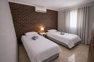 two beds in a room with a brick wall at Work, Rest, Repeat, Comfortable 2BR Flat in Kathu in Kathu