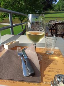 a glass of wine sitting on top of a table at Chambres de séjour et Brasserie du Coiroux in Aubazines
