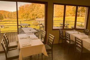 a restaurant with white tables and chairs and windows at Chambres de séjour et Brasserie du Coiroux in Aubazines