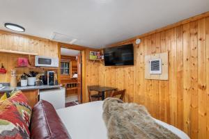 a living room with wooden walls and a kitchen with a couch at Timber Ridge Cabin: Rustic Getaway in Rapid City