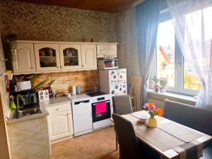 a kitchen with white cabinets and a table and a window at Diana Apartments in Klingenthal