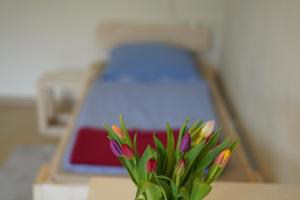 a vase with flowers in front of a bed at Haus Gänsefarm - Ihre Monteurs Wohnung - in Husby