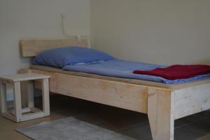 a wooden bed with a blue mattress and a table at Haus Gänsefarm - Ihre Monteurs Wohnung - in Husby