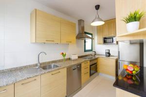 a kitchen with wooden cabinets and stainless steel appliances at Villa Sunshine Lanzarote by Villa Plus in Teguise